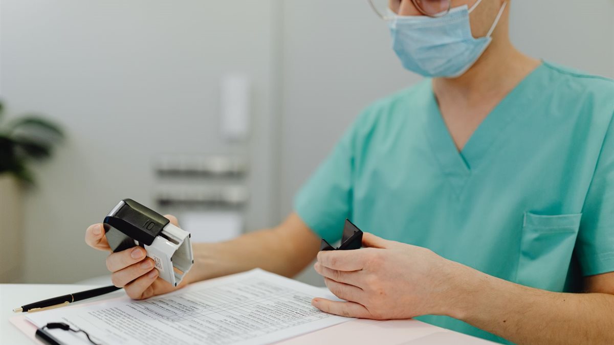 A clinician in scrubs reviewing patient paperwork on a clipboard